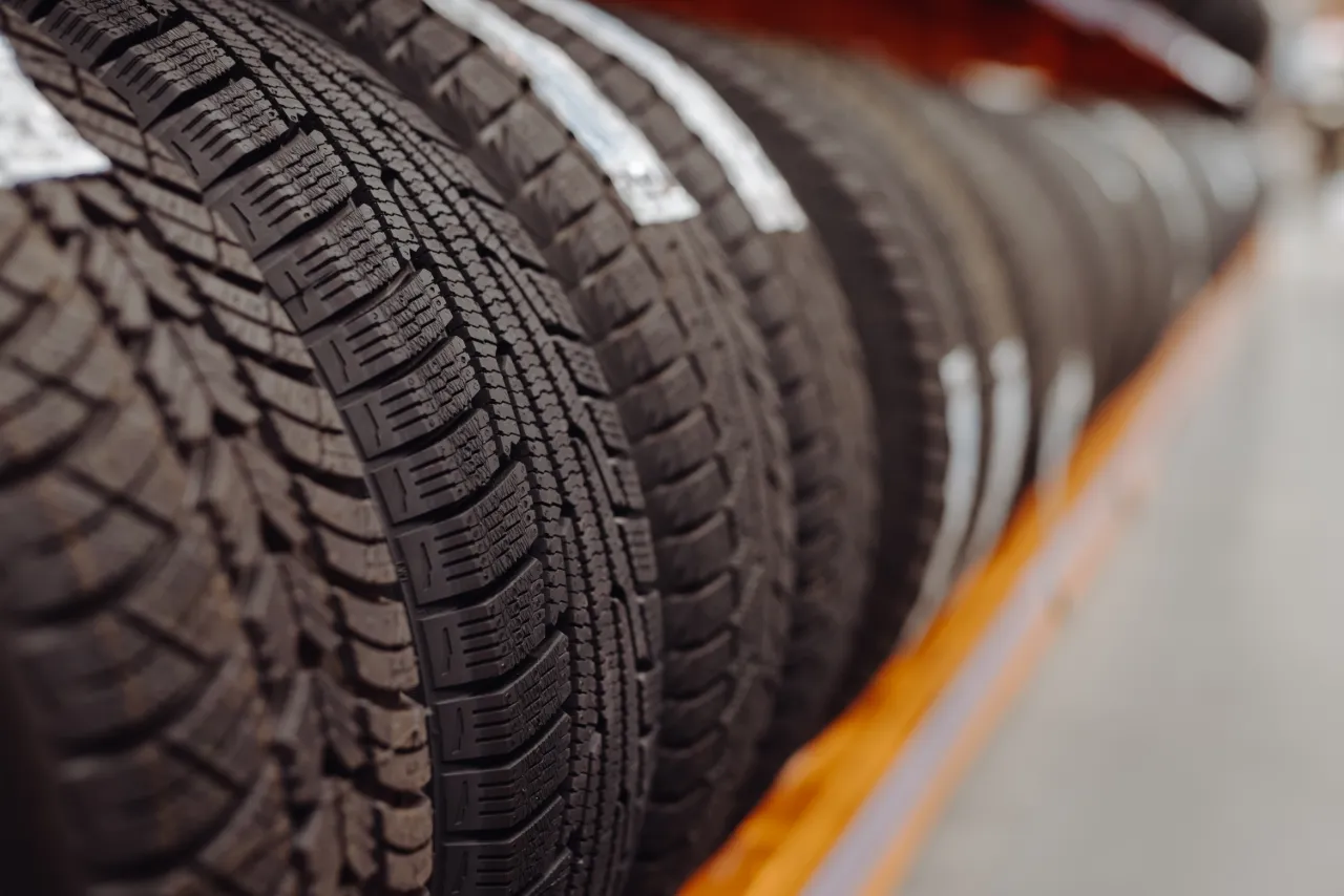 Close-up of multiple new car tyres displayed on a rack in a tyre shop 